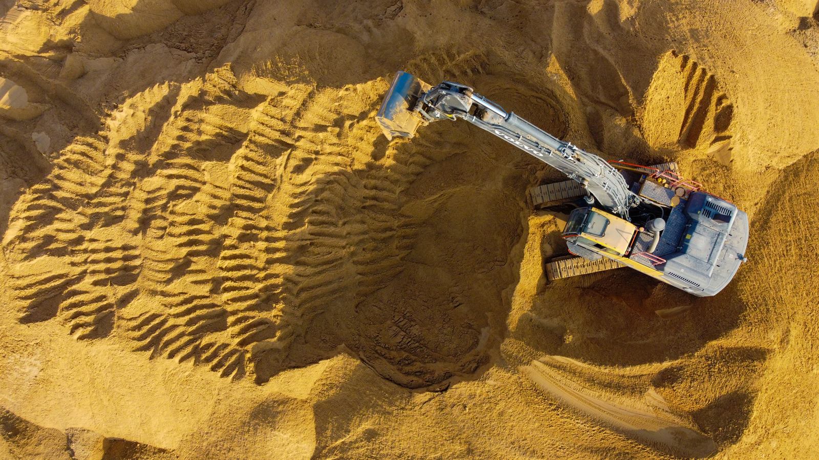 Excavadora hidráulica trabajando en zona de movimiento de suelos, vista aérea