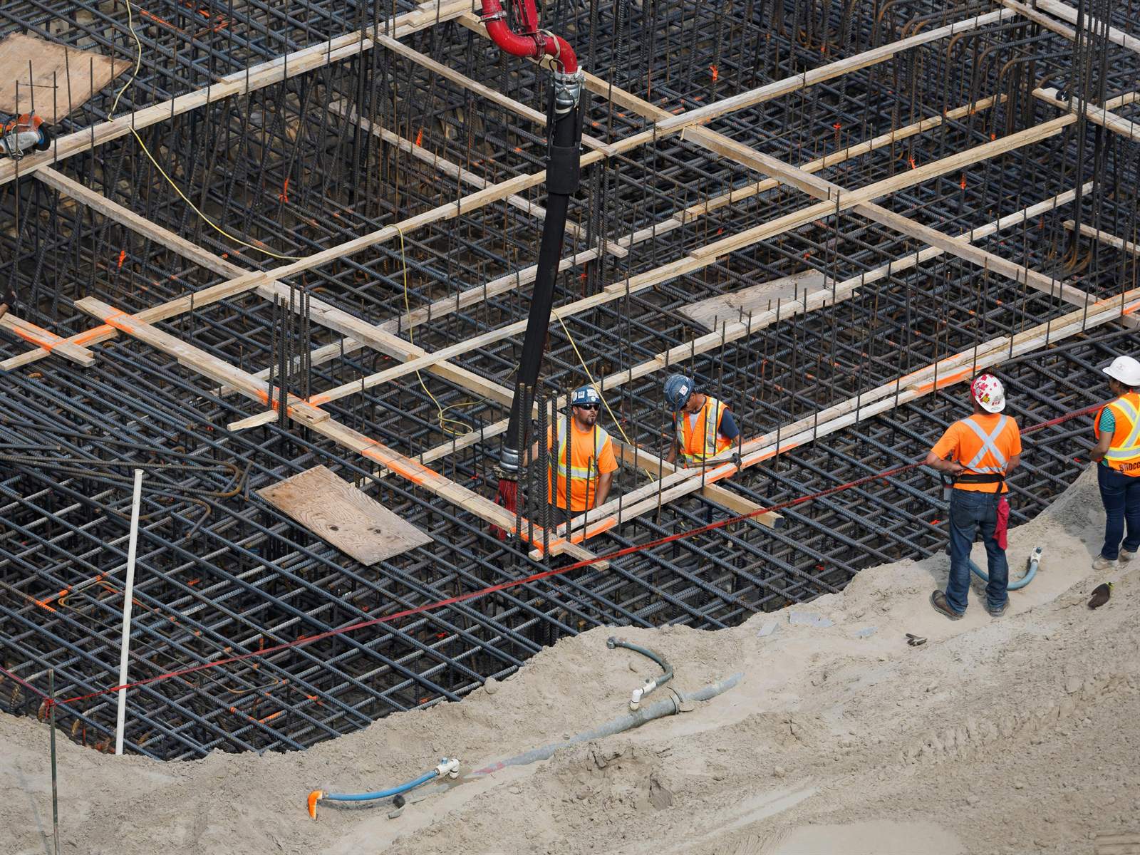 Cuadrilla de obra civil con equipo de protección personal trabajando sobre armadura de hierro