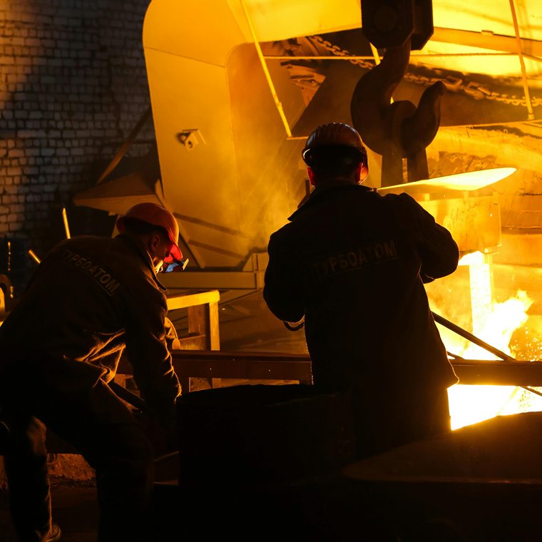 Operarios trabajando dentro de una acería junto a un horno de colada, control de procesos de industria pesada